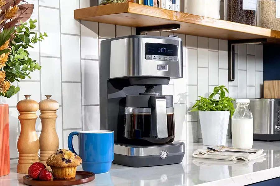 Stainless steel GE 12-Cup Drip Coffee Maker model G7CDAASSTSS brewing coffee in a modern kitchen setting.